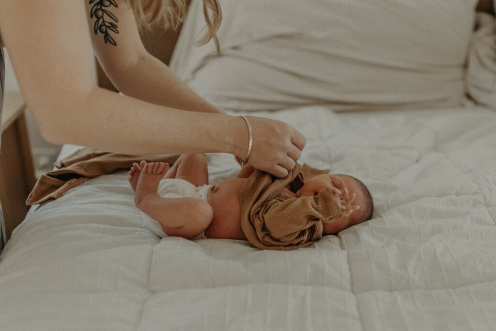 a baby laying on a bed being held by a woman