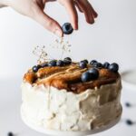 person holding black fruit near cake